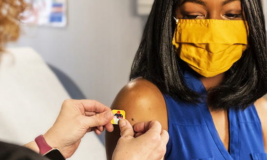 A woman in a mask receives a COVID vaccination