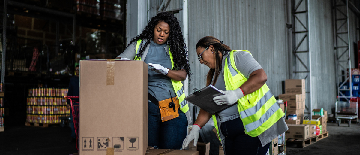 Two warehouse workers examine a box to determine its next destination