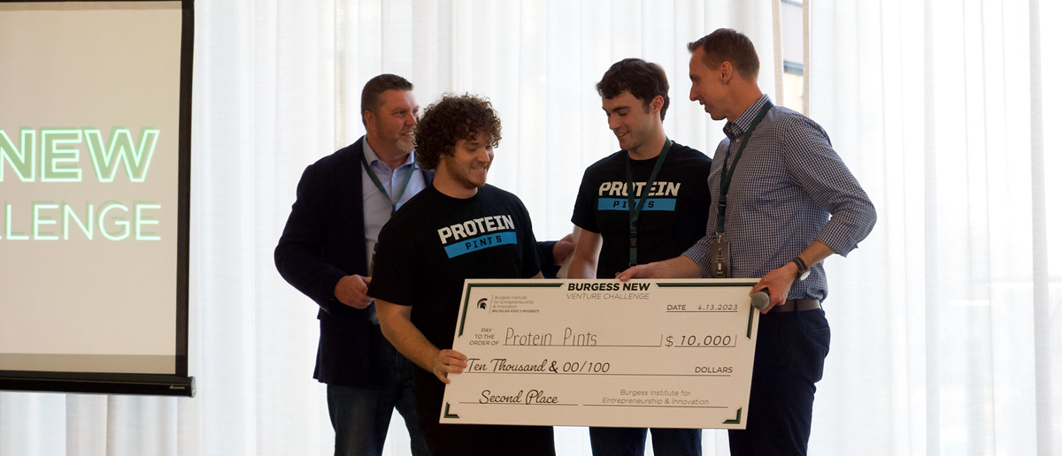 Founders of Protein Pints receive an oversized check for $10,000 from Ken Szymusiak and Paul Jacques