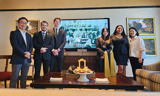 Members of the winning team pose in a hotel in front of a screen showing their presentation